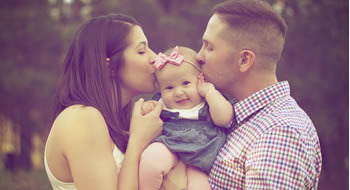 Family image for life insurance post, parents kissing each side of baby's face.